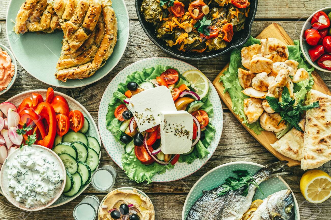 Selection of traditional greek food - salad, meze, pie, fish, tzatziki, dolma on wood background