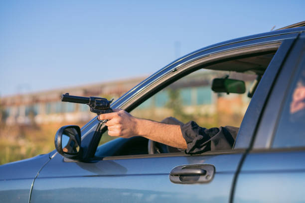 criminal shooting a gun through a window of a moving car