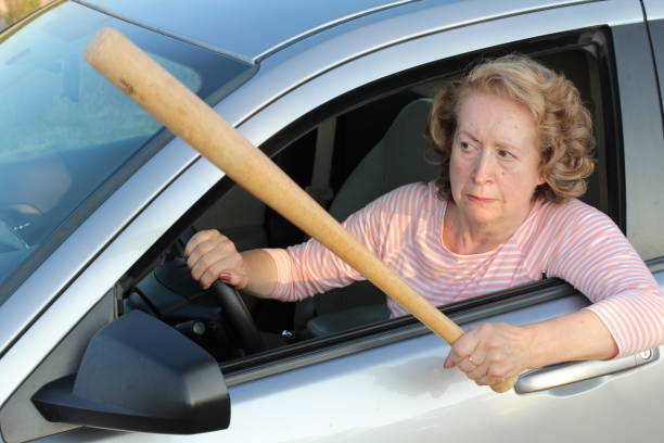 Angry mature female driver holding baseball bat.